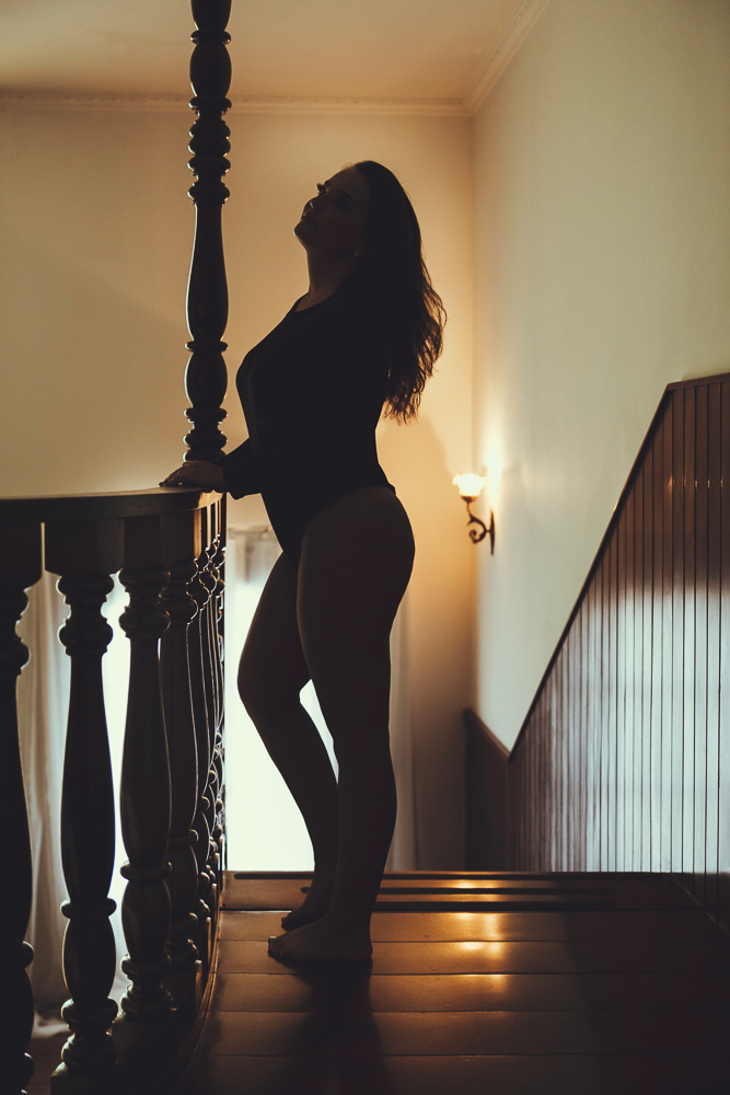 Fotografia em contraluz de mulher em mezanino em estúdio fotográfico para ensaio sensual
